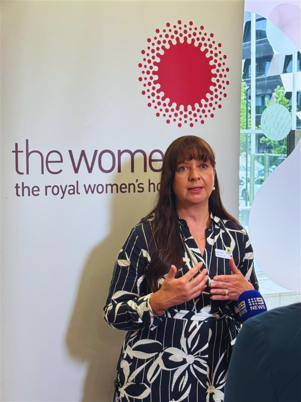 Lisa Lynch chief operations officer standing in front of media banner with news mic in front of her